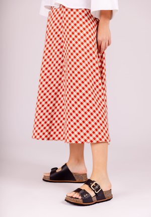 Red and white gingham patterned midi skirt, A-line shape, paired with black slide sandals featuring a cork sole and buckle detail.