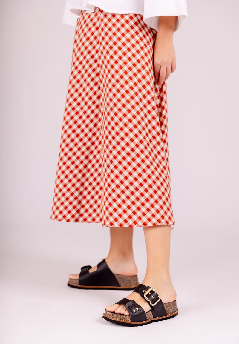 Rood-wit geruit midi-skirt in A-lijn, gecombineerd met zwarte slip-ons met kurken zool en gespsluiting.