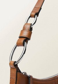 Bandoulière en cuir marron avec un connecteur en métal argenté et une texture lisse, ornée de coutures soignées le long du bord.