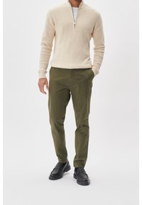 Beige zip-neck sweater, olive green chinos, and black loafers. Smooth texture, tailored fit, and subtle design details.