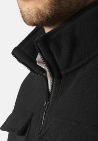 Schwarze Fleecejacke mit hohem Kragen, Reißverschluss und aufgesetzten Taschen. Die strukturierte Stoffoberfläche und das karierte Innenfutter sind sichtbar.