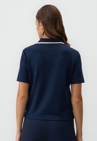 Marine polo shirt met korte mouwen, voorzien van een witte kraagafwerking, een soepele stoftextuur en een ontspannen pasvorm. Achteraanzicht weergegeven.
