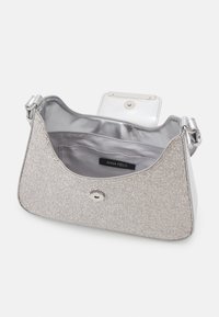 Stříbrná taška přes rameno z látky s magnetickým klopou, vnitřní kapsou a štítkem s nápisem "Anna Field" uvnitř podšívky.