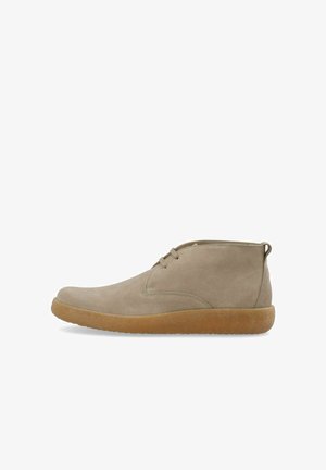 Bottes montantes en suède beige avec un bout arrondi, un laçage minimal et une semelle en caoutchouc présentant une finition texturée de couleur gomme.