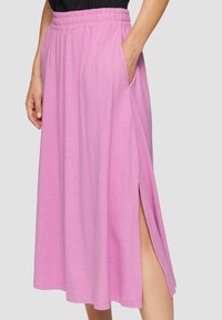 Light pink midi skirt with an elastic waistband and side pockets, featuring a slit on one side and a smooth, soft texture.