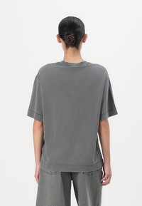 Oversized grijze katoenen t-shirt met korte mouwen, geribbelde ronde hals en zijslits aan de zoom, gecombineerd met bijpassende losse grijze shorts.