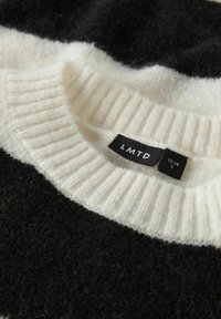 Czarnobiały sweter z dzianiny z prążkowanym białym kołnierzem. Metka pokazuje rozmiar S i markę "LMTD." Miękka tekstura z kontrastującymi paskami.