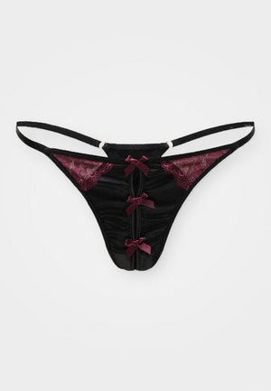 Black lace thong with burgundy lace accents, three satin bows at the front, and adjustable straps. Smooth texture with sheer details.