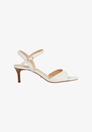 Witte leren hoge hak sandaal met een cross-strap ontwerp, een kleine gouden gesp accent en een gestructureerde houten hak. Open teen stijl.