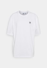 Biela bavlnená tričko s voľným strihom, s čiernym logom Adidas na ľavej hrudi. Krátke rukávy a okrúhly výstrih.