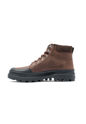 Botte de cheville en cuir marron avec semelle en caoutchouc, œillets en métal et bout noir contrastant. Présente des accents texturés et une conception robuste.
