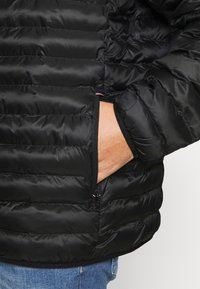 Schwarze Daunenjacke mit gestepptem Design, ausgestattet mit einer seitlichen Reißverschlusstasche und elastischen Bündchen. Das Material erscheint glatt und glänzend. Lässige Passform.