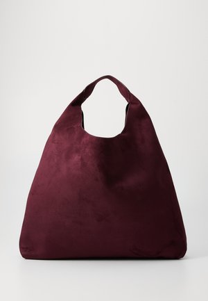 Geantă mare din suede burgundy închis, cu un singur maner lat și o formă triunghiulară relaxată, pe un fundal simplu.