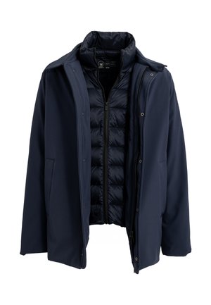 Cappotto soft-shell blu navy con foderato trapuntato, chiusura con zip e bottoni a scatto. Presenta un colletto classico e due tasche frontali.
