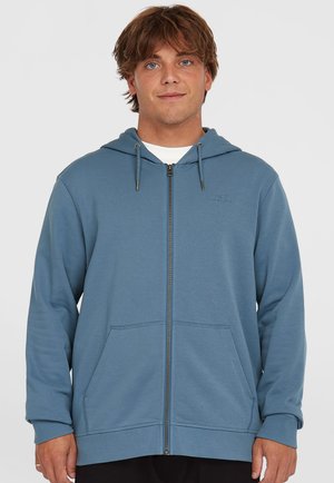 Blue zip-up hoodie made of soft fabric, featuring a hood, two front pockets, and a small logo on the left chest. Smooth texture.