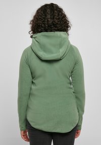 Green fleece hoodie with a large hood, fitted sleeves, and a curved hem. The fabric appears soft and textured.