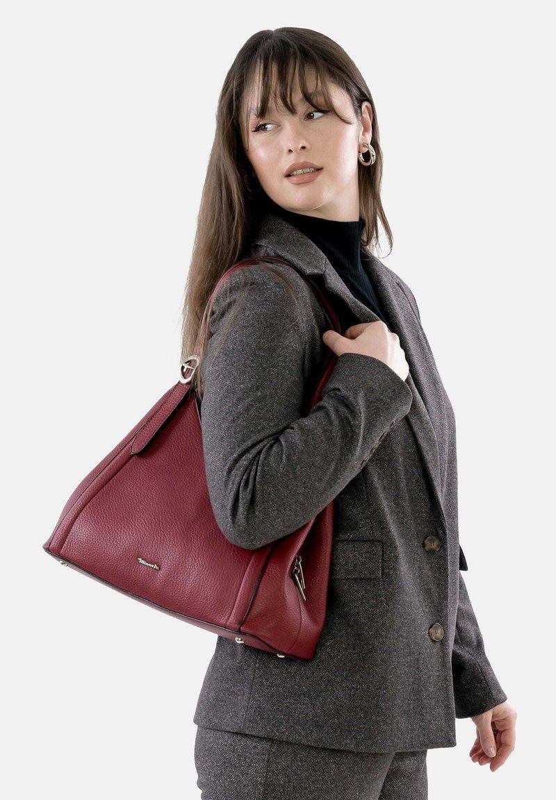 Rote Lederhandtasche mit strukturiertem Design, oberen Griffen und silbernen Hardware-Details. Strukturierte Oberfläche und dezentes Markenlogo sind vorhanden.