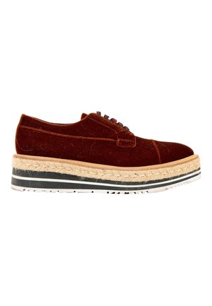 Chaussure à lacets en velours marron avec une semelle intermédiaire tissée épaisse et une semelle extérieure en caoutchouc rayée noir et blanc, vue latérale sur fond blanc.