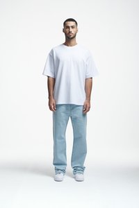 T-shirt oversized en coton blanc à manches courtes, associé à un jeans en denim bleu clair. Chaussures blanches en sneakers. Tenue simple et décontractée.