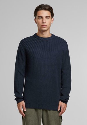 Suéter de punto acanalado en navy, con cuello redondo, manga larga y tejido texturizado. Presenta un corte holgado y puños y dobladillo acanalados.