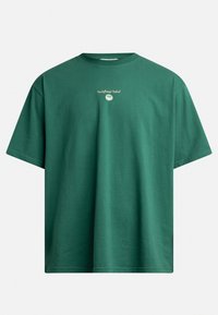 T-shirt en coton vert avec un col rond, des manches courtes, et une broderie frontale indiquant "Redefined Rebel." Texture lisse, coupe décontractée.