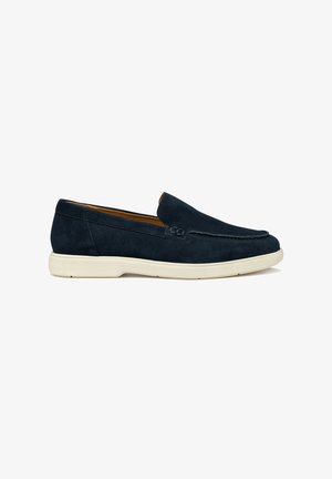 Mocasín de ante azul marino sin cordones con suela de goma blanca y costuras mínimas, perfil lateral, zapato de estilo casual.