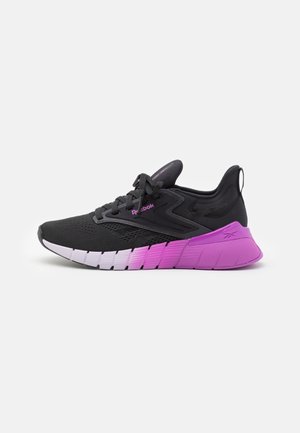 Zapatilla deportiva negra y morada con suela de degradado, parte superior de malla, diseño de cordones y logo de Reebok en el lado y la lengüeta del talón.