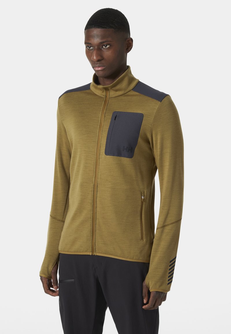 Zielono-oliwkowa kurtka zapinana na zamek z czarnymi akcentami, z kieszenią na piersi i jedną kieszenią na zamek z boku, wykonana z teksturowanej tkaniny.