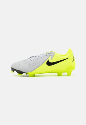 Futbalové kopačky so sivým zvrškom s rebrovanou textúrou, jasne žltými akcentmi a čiernym logom Nike. Podrážka má viditeľné kolíky pre trakciu.