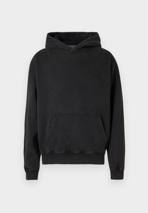 Haut à capuche noir en tissu doux. Dispose d'une grande poche avant, d'une capuche avec cordon de serrage et de poignets et ourlet côtelés.