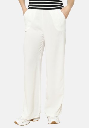 Lightweight, loose-fitting white pants with a smooth texture and side pockets, paired with white sneakers and a black and white striped top.