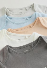 Keturių medvilninių marškinėlių rinkinys su gofruotais apykaklėmis pilkos, baltos, pastelinės mėlynos ir persikų spalvų. Lygus tekstūras su etiketėmis ir minimaliais dizaino elementais.