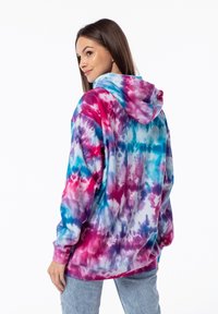 Felpa con cappuccio in tinta unita che presenta motivi a vortice nei colori rosa, viola e blu, maniche lunghe e una vestibilità comoda con tasca a marsupio.