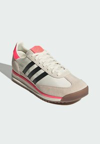 Béžové a šedé semišové tenisky s černými pruhy, růžovými akcenty na patě a jazyku a texturovanou gumovou podrážkou.