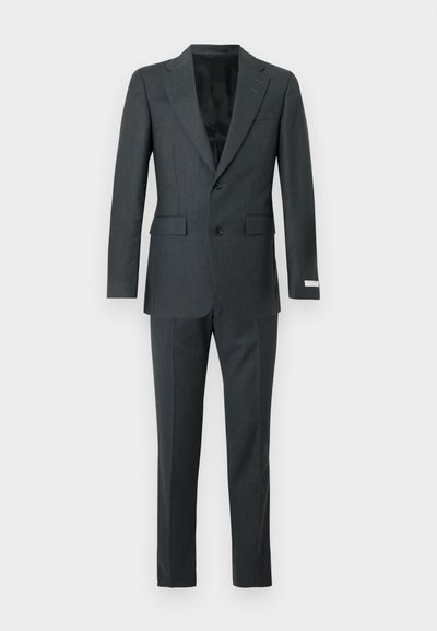 Σκούρο γκρι κοστούμι δύο τεμαχίων με σακάκι με notch πέτο, κλείσιμο με δύο κουμπιά, τσέπες με καπάκι και ταιριαστά tailored παντελόνια σε μονόχρωμο φόντο.