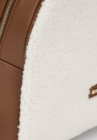 Bruin leer en witte tekstiel combineren in deze tas, die een ritssluiting heeft en een klein gouden logo-accent aan de zijkant.