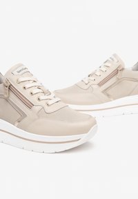 Beige sneakers van een mix van glad en geperforeerd faux leren, voorzien van veters en een zijrits, afgewerkt met een witte zool.