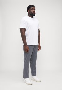Hvit bomulls t-skjorte kombinert med grå, teksturerte dressbukser. Overtøyet fullføres med hvite sneakers med et logo-accent.