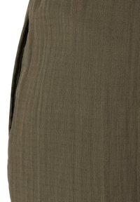 Oliemgroene gestructureerde stof met zichtbare diagonale weef en subtiele verticale stiklijnen, met een zijnaad en een zakopening.