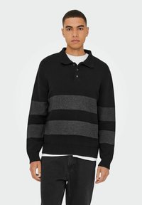 Schwarzer Pullover mit Kragen, der horizontale graue Streifen und gerippte Bündchen aufweist. Der Stoff wirkt strukturiert und weich.