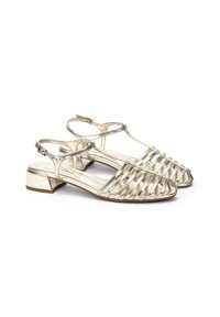 Sandalias de slingback doradas metálicas con diseño de punta abierta, que cuentan con recortes a rayas, un tacón bajo y una correa en el tobillo con hebilla ajustable.