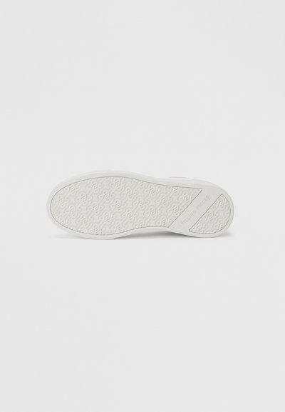 Λευκή σόλα παπουτσιού με υφή σχεδίου από κυματιστές γραμμές και το εμπορικό όνομα "FILLING PIECES" ανάγλυφο κοντά στην περιοχή της φτέρνας.