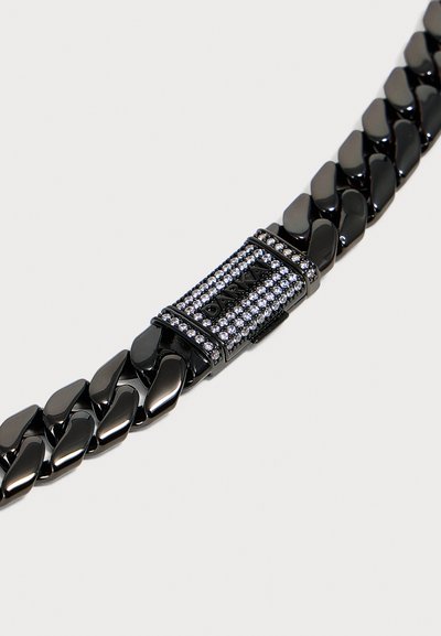 Bracelet chaîne en métal noir avec fermoir rectangulaire incrusté de petits cristaux clairs et "DARK" gravé sur le fermoir.