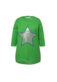 Chemise en coton verte avec un design d'étoile en sequins argentés bordé de bleu. Elle présente un col en V et des bords effilochés aux manches et au col.