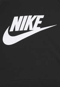 Czarna tkanina z dużym białym logo Nike i charakterystycznym znakiem Swoosh wyraźnie widoczne na przodzie.