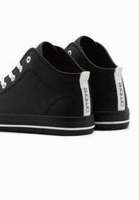 Svarta låga sneakers tillverkade av texturerat material. Funktioner vita snören, en vit accent på hälen och ett tunt vitt streck på sulan.