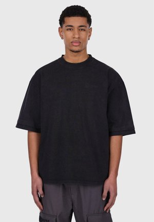 Black oversized T-shirt made of cotton, featuring a crew neckline, short sleeves, and subtle branding on the chest.