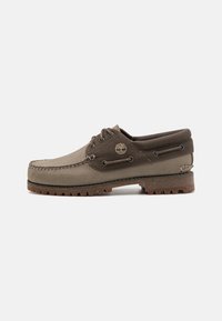 Schnürbootsschuh aus grauem Canvas und Leder, mit einer Gummi-Außensohle, kontrastierenden braunen Akzenten und dekorativen Steppdetails.