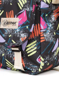 Zaino nero con motivi astratti multicolori; presenta una chiusura a pattina, una tracolla regolabile e una piccola etichetta del marchio. Tessuto testurizzato.