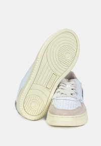 Sneakers bianchi in pelle con accenti in suede beige, dettagli perforati e suola in gomma testurizzata. Presentano lacci e branding sul lato.